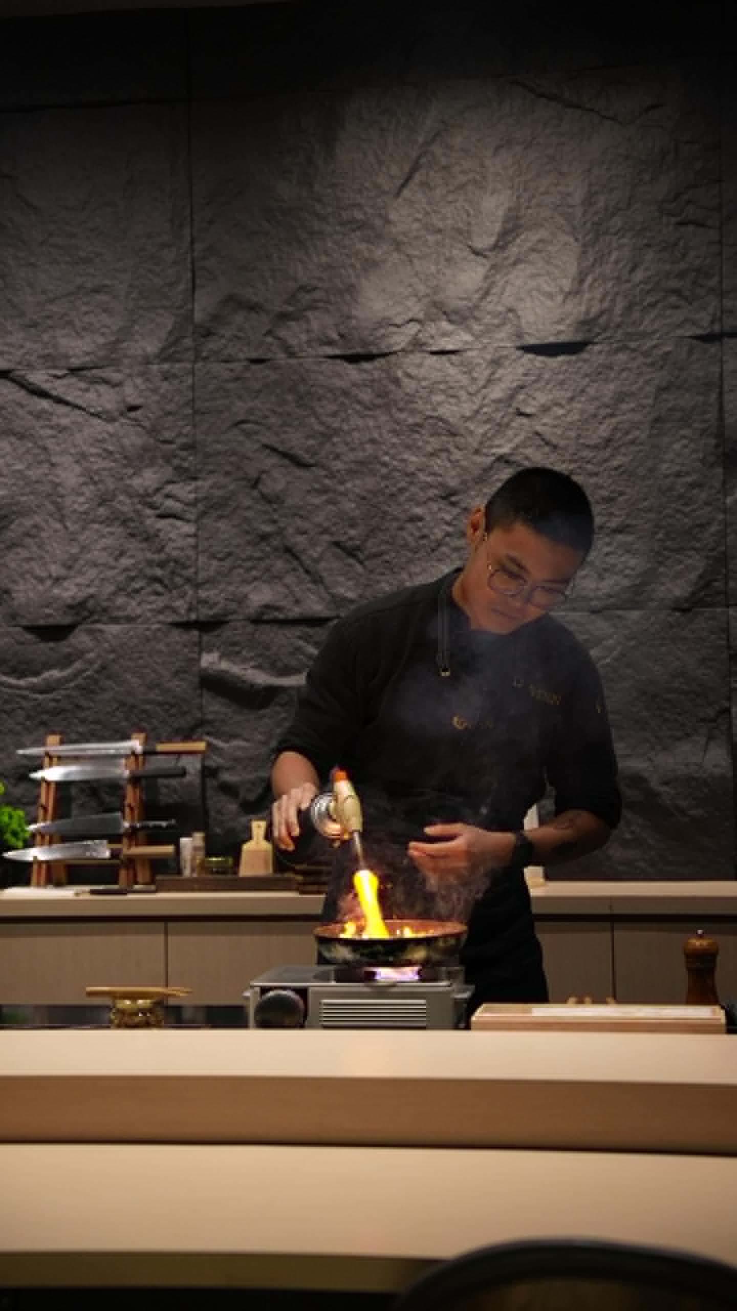 Desmond, the executive head chef, firing a pan with a blowtorch at the DEN Culinary counter