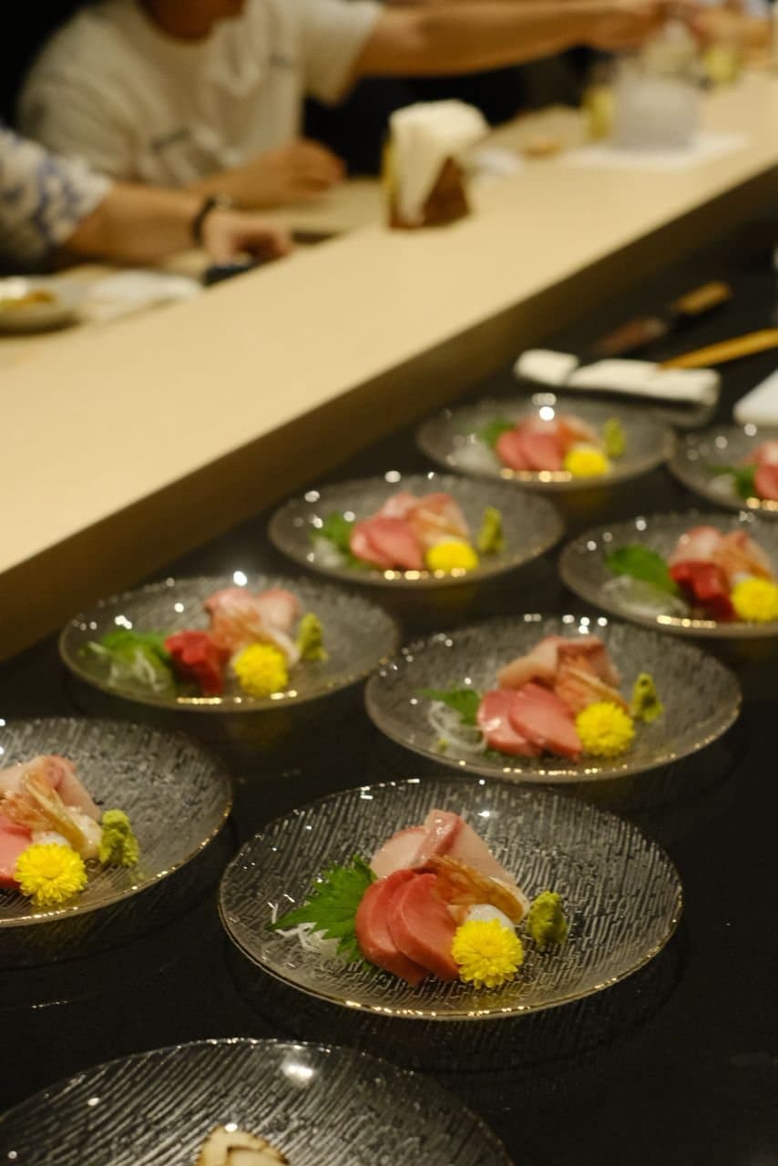 A line of sashimi plates set along the counter
